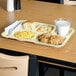 A Carlisle tan 6 compartment tray with food on a table.