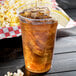 A Solo Ultra Clear PET plastic cup of iced tea with a lemon wedge and popcorn.