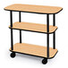 A Geneva 3 shelf tableside service cart with a maple finish on wheels.