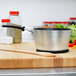 A Vollrath Wear-Ever sauce pan with a black handle on a cutting board with vegetables.