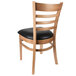 A Lancaster Table & Seating wooden restaurant chair with a black vinyl cushion.