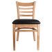 A Lancaster Table & Seating wooden ladder back chair with black vinyl seat.
