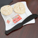 A piece of bread on a plate with a Fineline black plastic sandwich spreader.