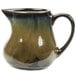 A green and brown Tuxton China creamer with a handle.