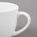 A close-up of a Tuxton white china Milano mug with a white handle.