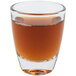 An Arcoroc shot glass filled with brown liquid on a white background.