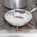 A Vollrath Wear-Ever aluminum pan cover with a Torogard handle on a pan on a stove.