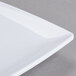 A white Thunder Group square melamine plate with a curved edge.