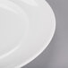 An Arcoroc white porcelain service plate with a rim.