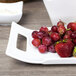 A white rectangular porcelain platter with handles full of fruit.