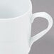 A close-up of a white Arcoroc stackable coffee mug with a handle.