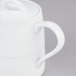 A white Arcoroc teapot with a lid on a gray surface.