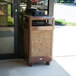 A Rubbermaid brown square steel waste receptacle with desert brown stone panels and a weather urn.