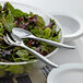 A bowl of salad with Visions silver plastic serving spoons.