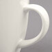 A close-up of a Tuxton white China mug with a handle.