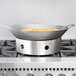 A Town stainless steel wok ring on a stove with a wok in it.