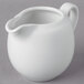 A 10 Strawberry Street Whittier white porcelain creamer with a handle on a gray surface.