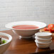 A table set with a bowl of soup in a 10 Strawberry Street Whittier white porcelain rim soup bowl.