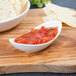 A bowl of salsa and chips on a wooden board.