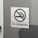 A Tablecraft stainless steel no smoking sign on a glass door.