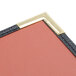 A close up of a corner of a red leather Menu Solutions Royal Select menu cover with gold trim.