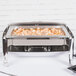 A Vollrath stainless steel roll top chafing dish on a table with shrimp and vegetables in it.