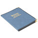 A blue Menu Solutions Royal Select Series leather-like menu cover with gold trim and a gold logo on a table.