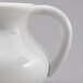 A close up of a white plastic creamer with a handle.