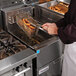 A chef using a Frymaster natural gas floor fryer to cook food in a basket.