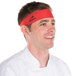A man wearing a red Headsweats headband in a professional kitchen.