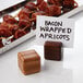 A bacon wrapped apricot on a wooden stick in an American Metalcraft olive wood table card holder.