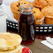An American Metalcraft glass milk bottle next to a plate of muffins and a stack of pancakes.
