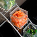 A metal stand with glass containers filled with vegetables including broccoli and carrots.