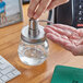 A hand using an American Metalcraft condiment mason jar to dispense soap.