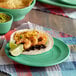 A Tuxton Concentrix cilantro green plate with shrimp and cheese tacos, lime wedges, and guacamole.