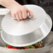 A person using a Town aluminum wok cover to steam vegetables in a bowl.