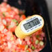 A Taylor 9878E yellow digital pocket probe thermometer on a pile of tomatoes.