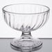 An Arcoroc clear glass dessert dish with a small rim on a table.