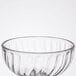 A close up of a clear Arcoroc dessert bowl with a curved wavy design.