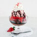 A bowl of ice cream with strawberries and chocolate syrup in a Swirl Optic dessert dish.