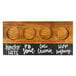 A Cal-Mil Madera natural wooden flight tray with circles and white writing on it.