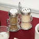 An American Metalcraft mini glass shaker caddy holding salt and pepper shakers on a table.