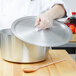 A chef using a Vollrath Arkadia lid on a pot.