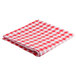 A folded red and white checkered Intedge vinyl table cover on a table.