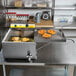 A Carnival King Funnel Cake Fryer on a school kitchen counter with food in it.