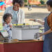 A woman and two children at a food stand with a Carnival King Funnel Cake Fryer.