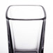 A close up of an Arcoroc clear tall square shot glass with a black rim.