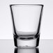 An Arcoroc clear shot glass on a white surface.