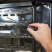 A person using a screwdriver to install a black cable on an Alto-Shaam Combitherm oven.
