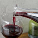A glass of red wine being poured from an Arcoroc square glass carafe.